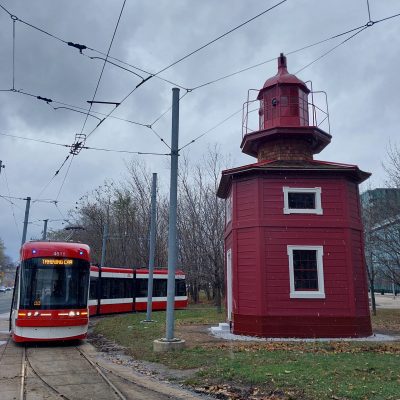 A red streetcar next to a red wooden building