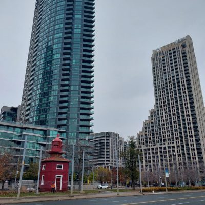 A small red building with tall condo buildings in the background