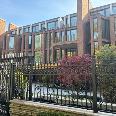 Beautiful brown brick condo building with a black fence and nice landscaping