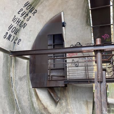 Interior of a concrete sphere with a bridge and graffiti