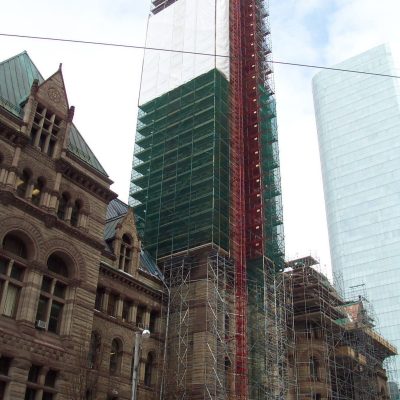 Covered scaffolding around the tower of an older looking brown building